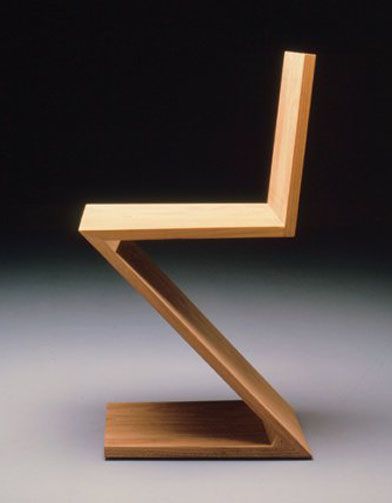 a wooden chair sitting on top of a white table next to a black wall and floor