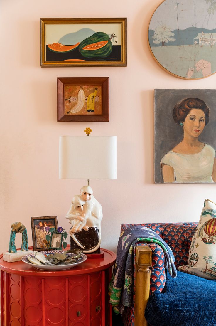 a living room with pink walls and pictures on the wall, including a red table