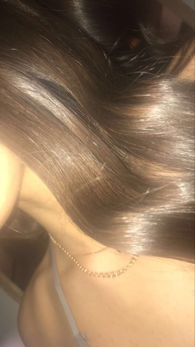 the back of a woman's head with long, shiny hair and necklace on