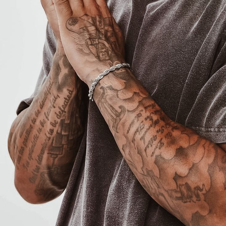 a man with tattoos holding his hands together