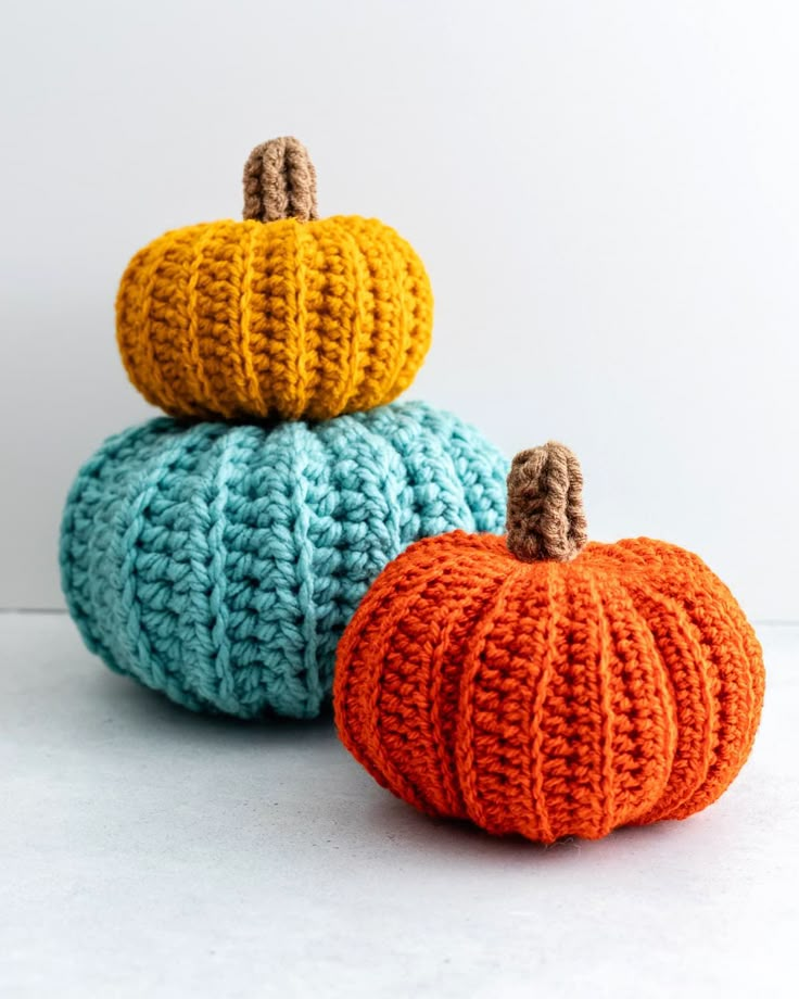 two crocheted pumpkins sitting on top of each other