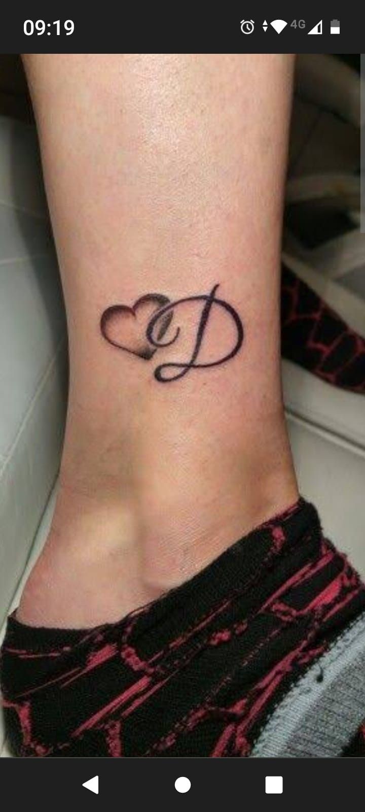 a small foot tattoo with the letter d on it's side ribcage