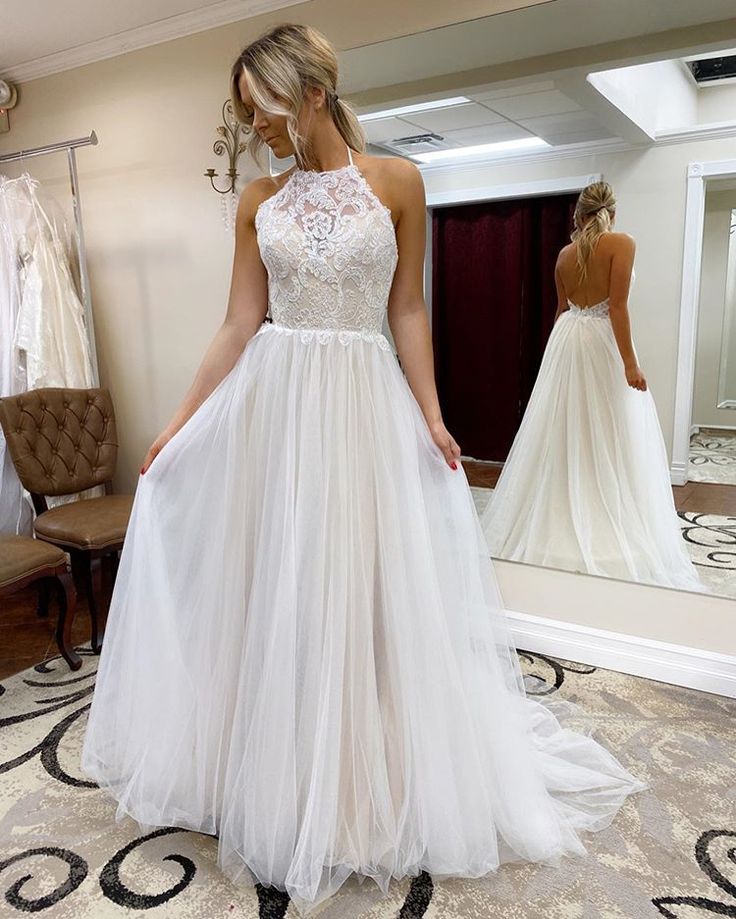 a woman standing in front of a mirror wearing a white dress with sheer neckline