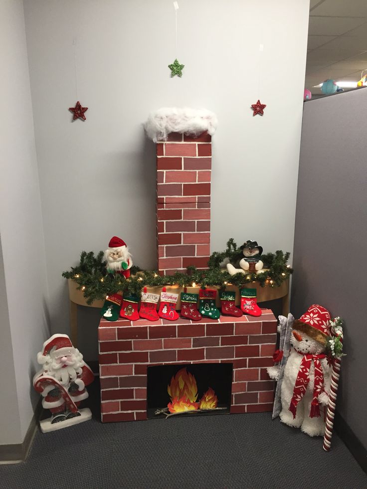 an office cubicle decorated for christmas with santa claus and snowmen around the fireplace