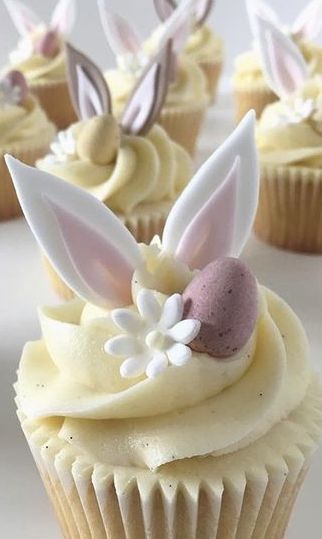 some cupcakes with bunny ears and flowers on them are decorated in white frosting