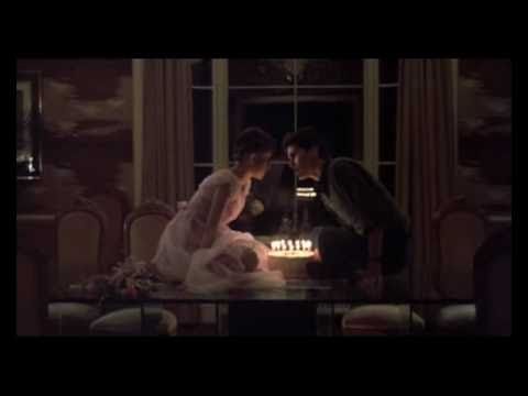 a bride and groom sitting in front of a cake with lit candles on it at night