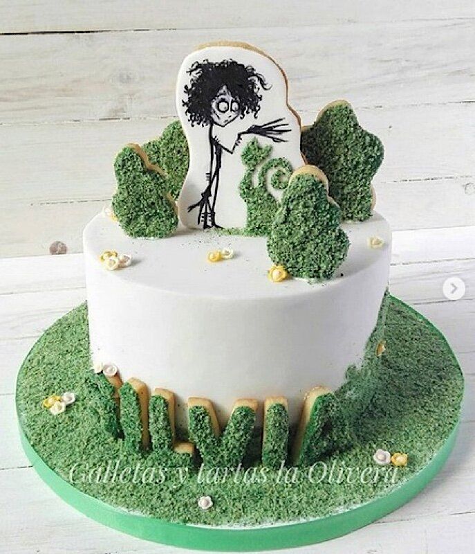 a cake decorated with green grass and gold trimmings on a white wooden table