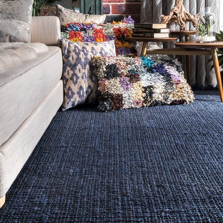 a living room filled with lots of pillows and blankets on top of a blue rug