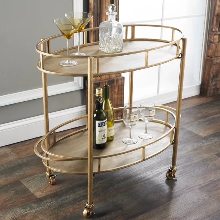 a gold bar cart with two wine glasses on it