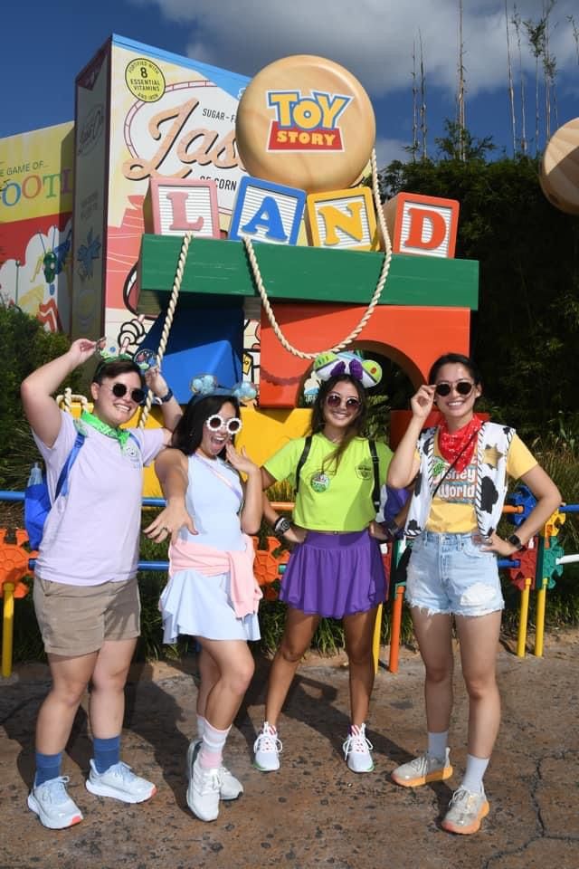 three girls are standing in front of a toyland sign and posing for the camera