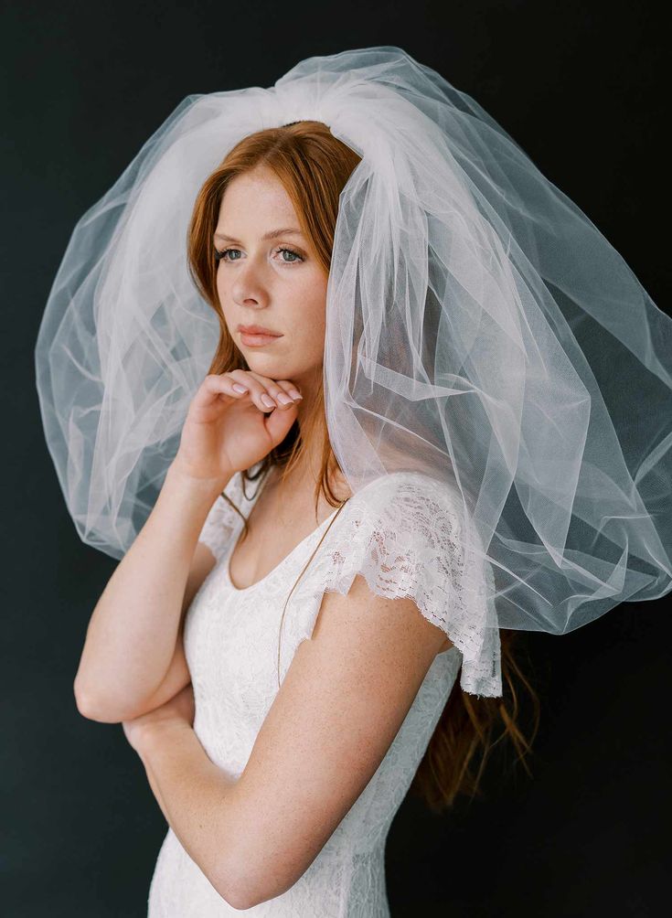 a woman with a veil on her head is posing for a photo in front of a black background