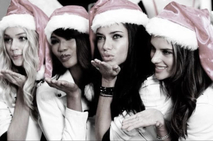 three beautiful women wearing santa hats posing for the camera