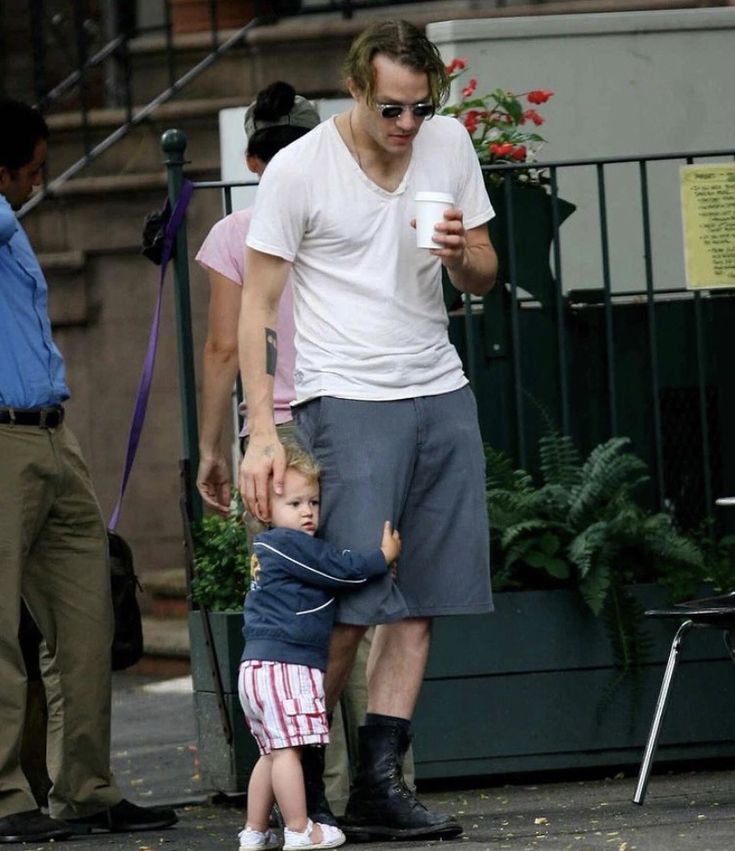 a man holding onto a small child's hand as they walk down the street