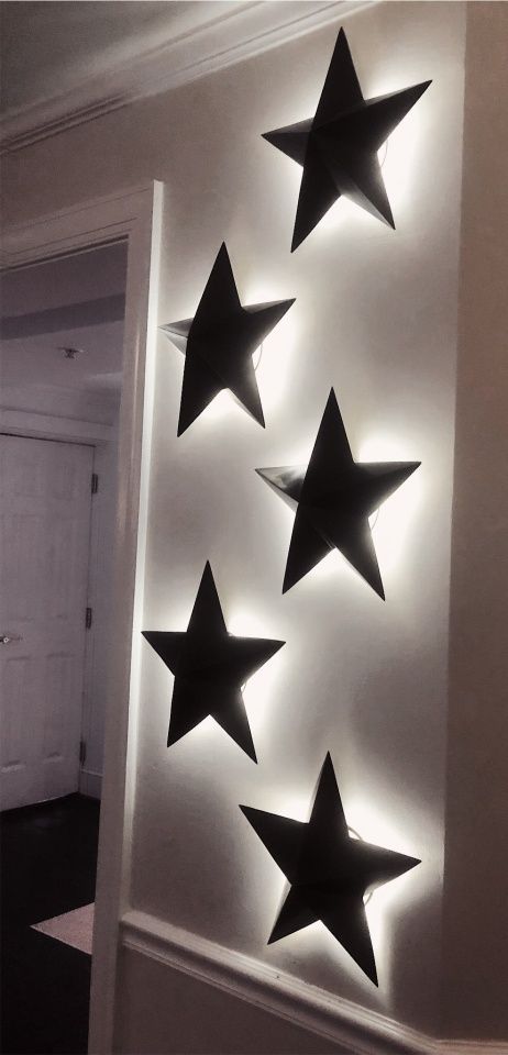 five black stars are mounted on the wall in front of a white door with light coming from it