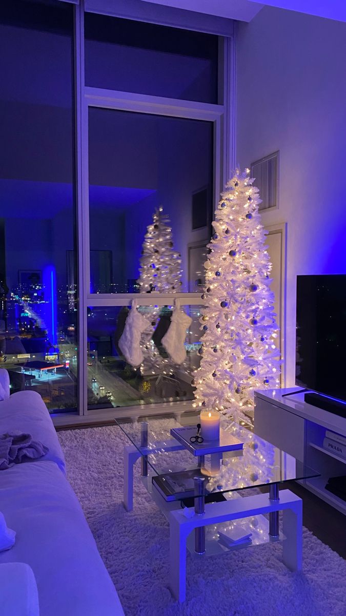 a living room with a white christmas tree in the center and blue lights on the walls