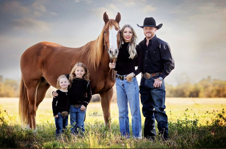 a family poses with their horse in an open field