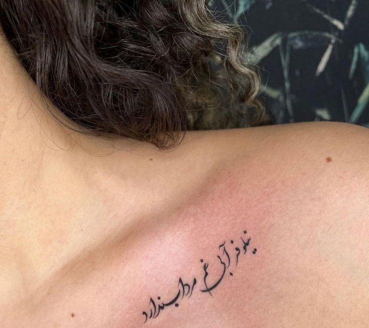 the back of a woman's shoulder with arabic writing on her left arm and chest