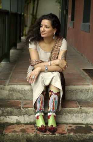 a woman sitting on the steps with her legs crossed wearing colorful socks and green boots