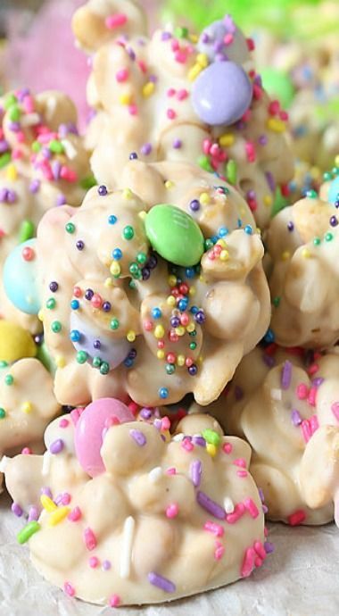 a pile of cookies with sprinkles and candy on top, sitting on a table