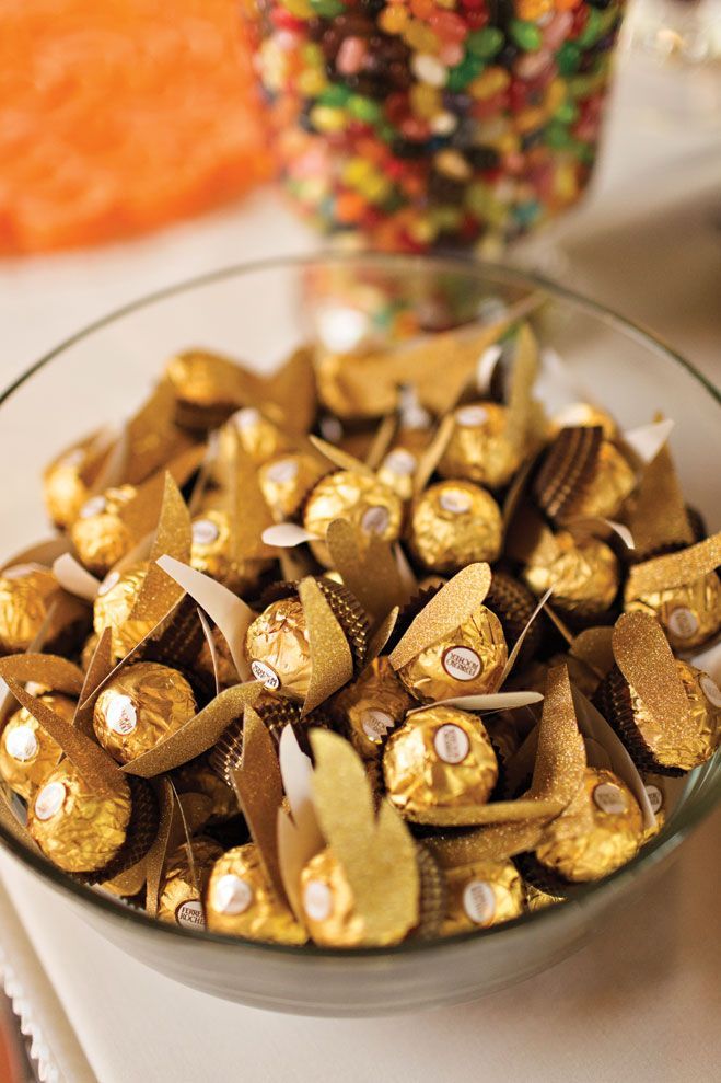 a glass bowl filled with gold foiled candies on top of a white table