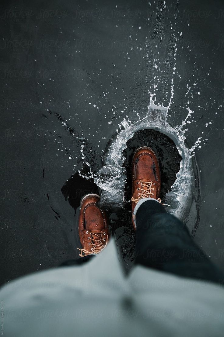 a person wearing brown shoes standing in the water