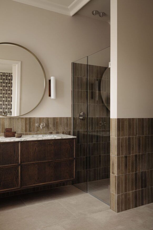 a bathroom with a sink, mirror and walk in shower stall next to a tiled wall