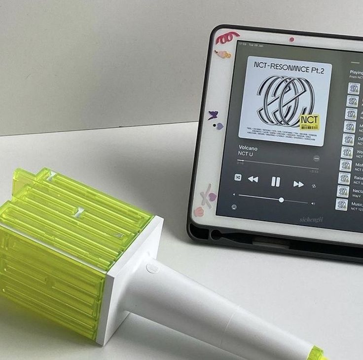 an electronic device sitting on top of a table next to a green brush and remote control