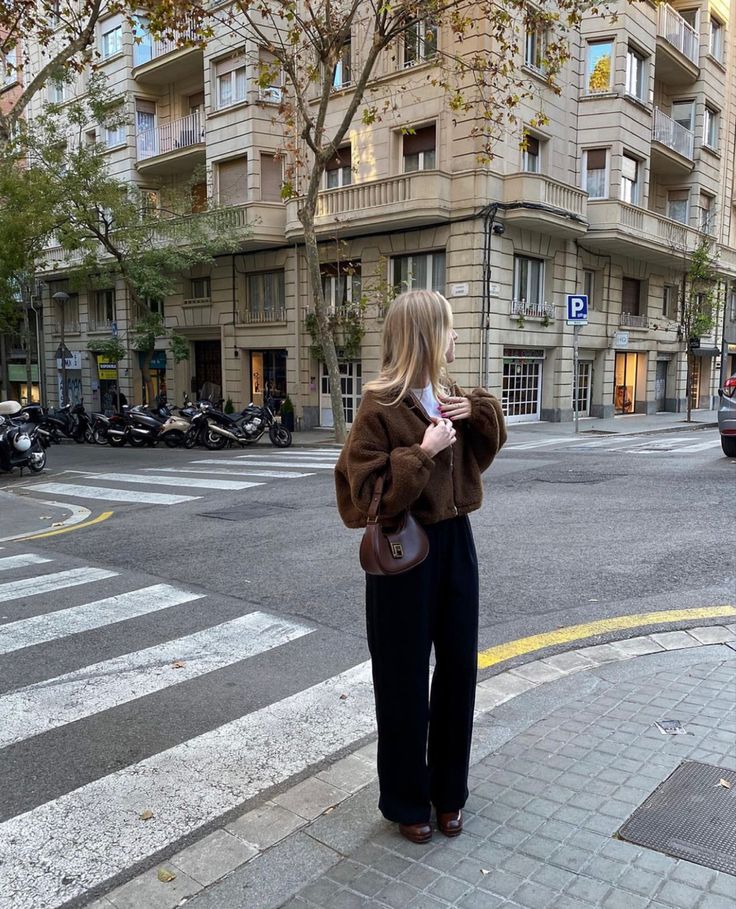 a woman is standing on the sidewalk talking on her cell phone