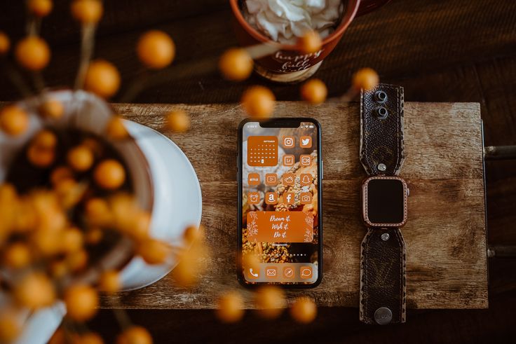 an iphone sitting on top of a wooden table next to a cup and saucer