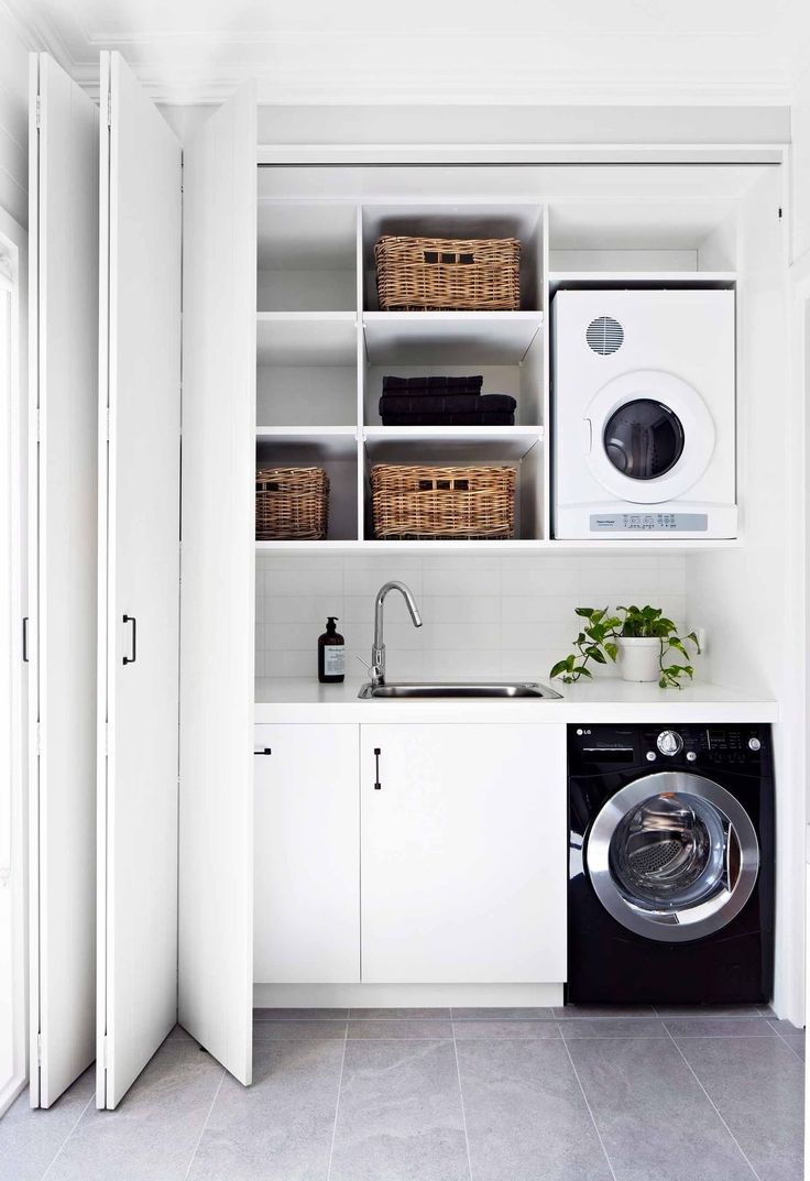 a washer and dryer in a white laundry room with open shelve