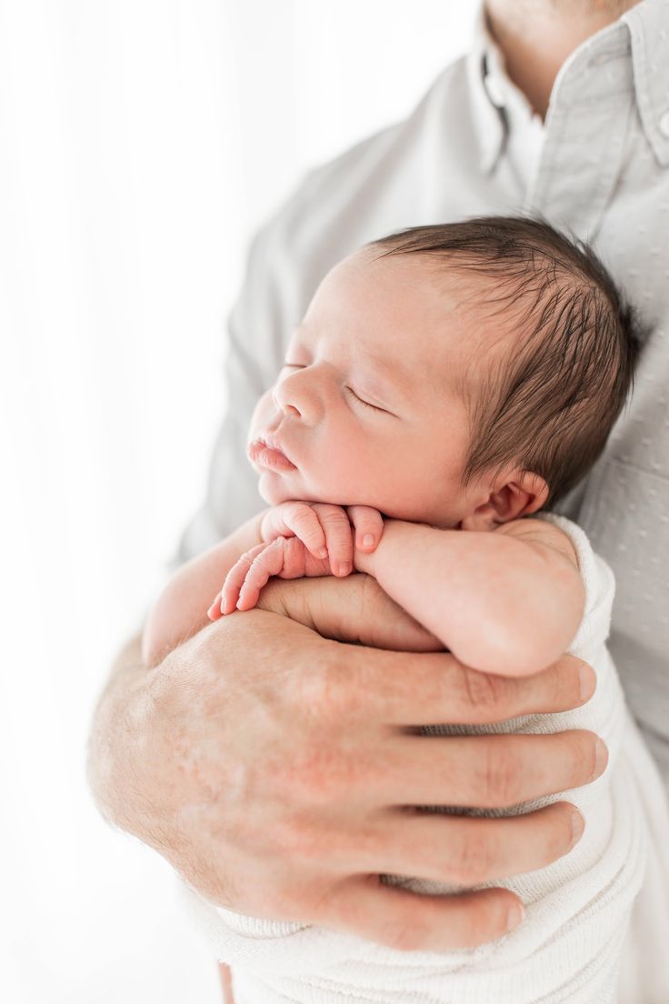 a man holding a sleeping baby in his arms