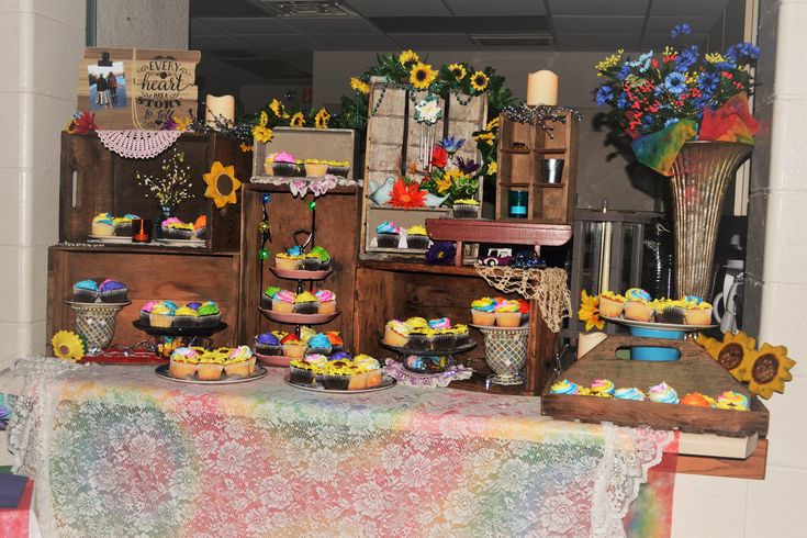 a table topped with cakes and cupcakes covered in frosting next to flowers