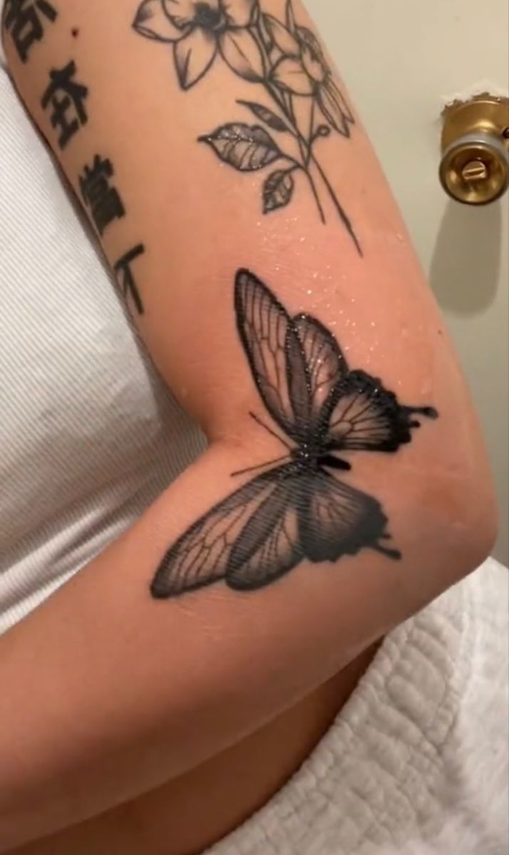 a woman's arm with a butterfly tattoo on it and chinese writing in the background