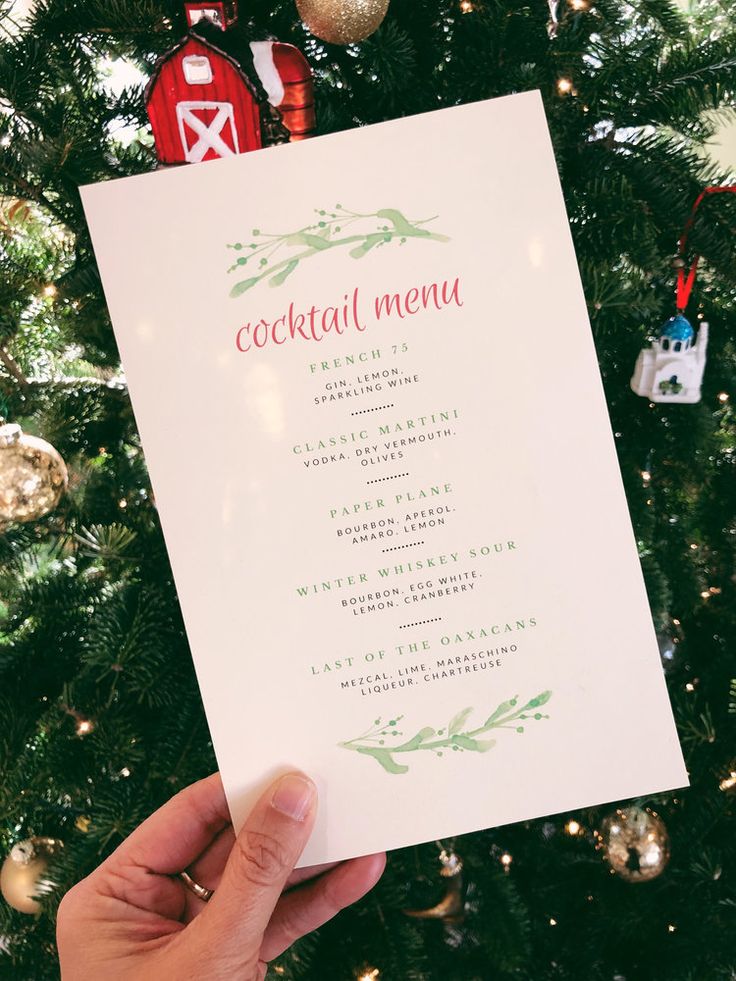 someone holding up a menu in front of a christmas tree