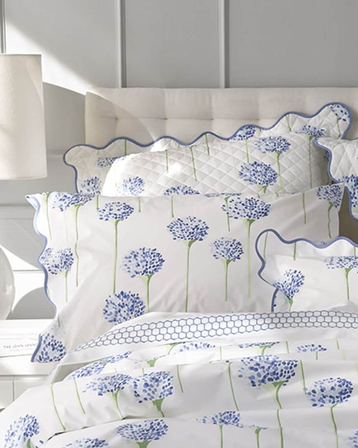 a bed with blue flowers on it in a room next to a lamp and window