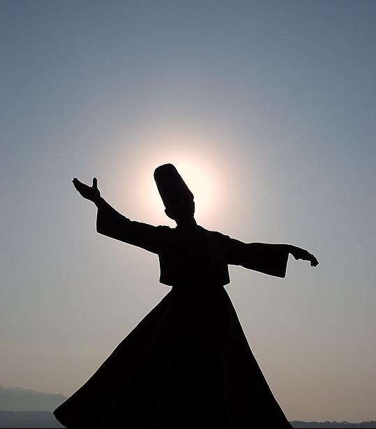 the silhouette of a woman in a long dress with her arms spread out to the sun