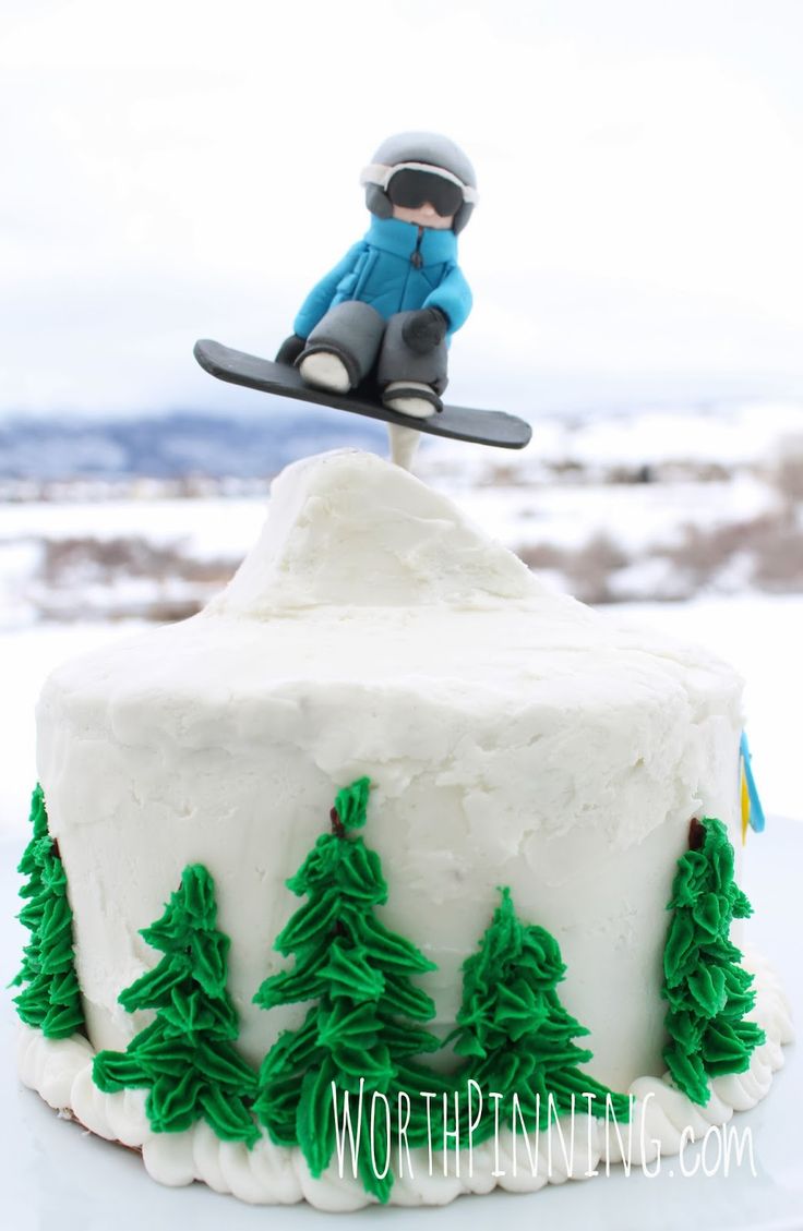 a snowboarder is jumping over a cake with trees on the bottom and green frosting