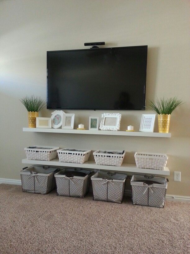 a flat screen tv mounted to the side of a wall next to baskets and plants