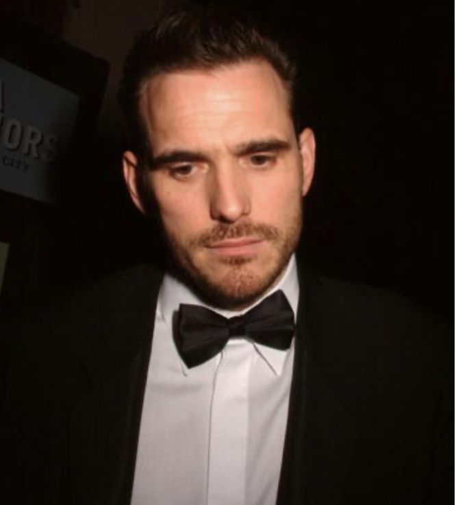 a man in a tuxedo and bow tie looking at the camera while wearing a suit