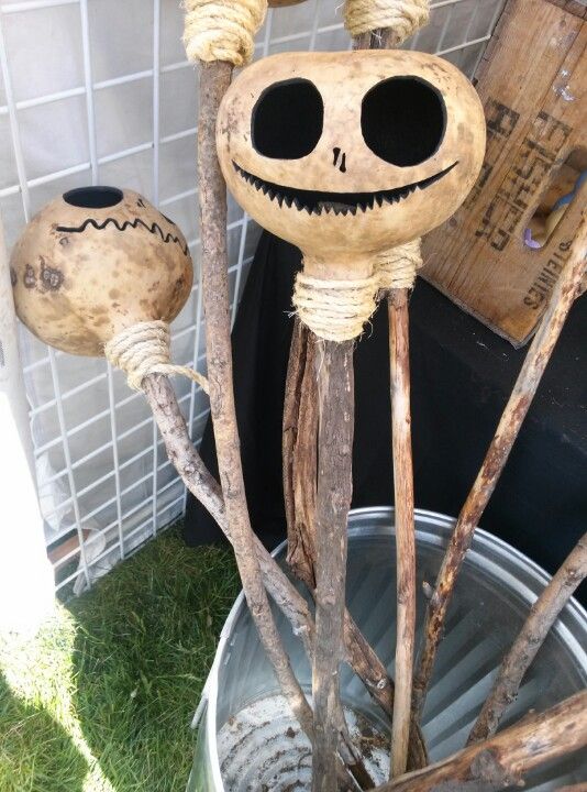 two wooden sticks with faces on them sitting in a bucket