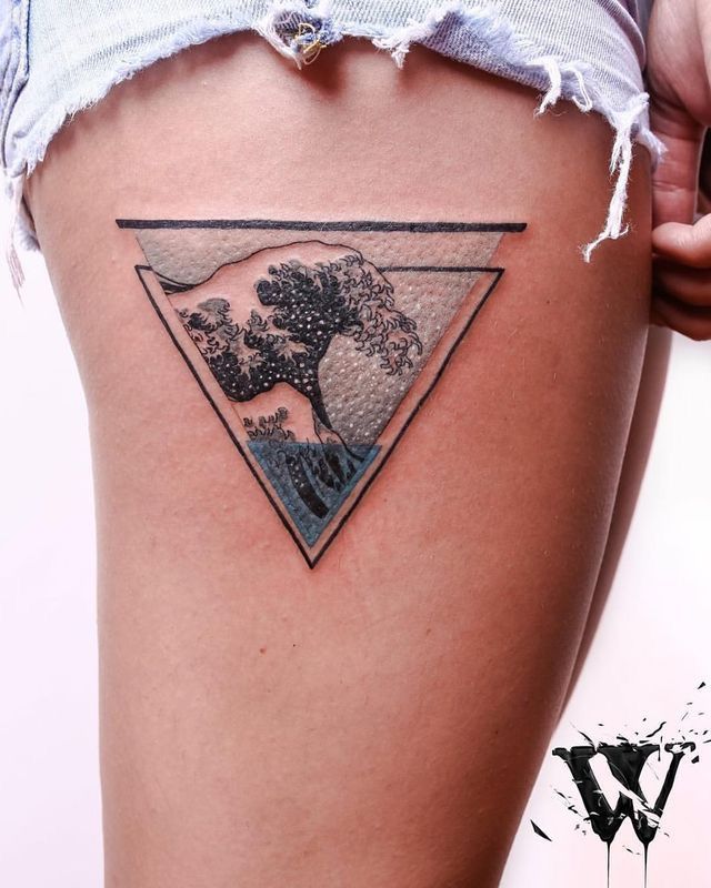 a woman's thigh with a tree and wave tattoo on her left side leg