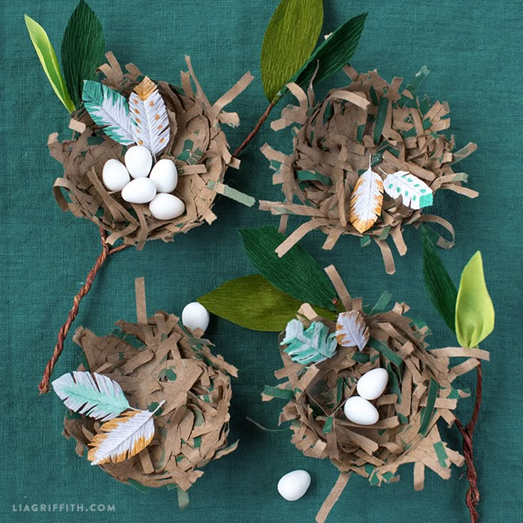 three bird's nests with eggs and leaves on a green cloth covered table