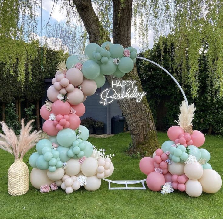 an outdoor birthday party with balloons and palm trees in the back yard, including a cake arch