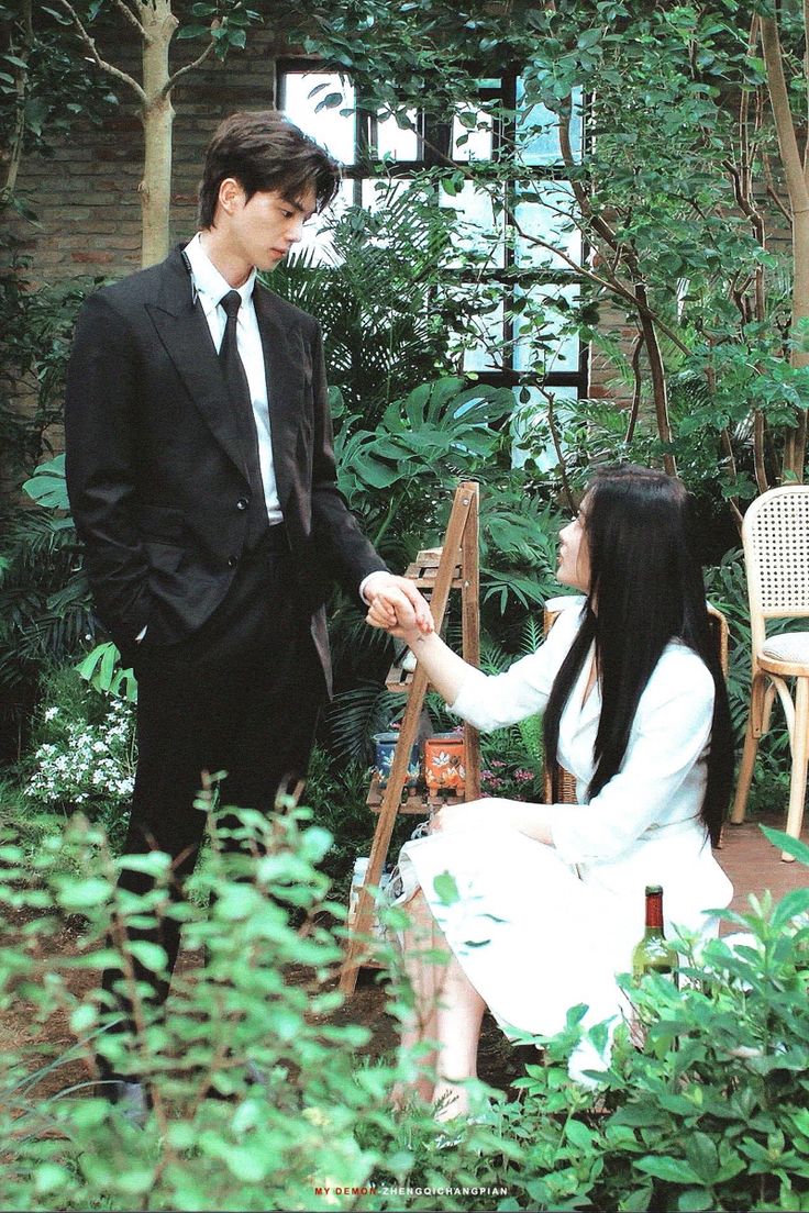 a young man and woman in formal attire standing next to each other, holding hands