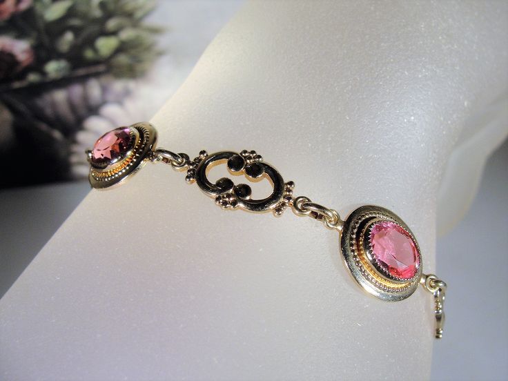 "This is a beautiful rose pink bracelet that is 14k Gold Filled. There are 4 oval cut faceted rosy pink glass gems with a decorative scroll link in between each. The look is stunning! Size of the bracelet is 7.25 inches. It has a round twist closure and a safety chain that is also able to be released and attached with the same type of closure. *Hang Tag reads: AMCO, 1/20 14K Gold Filled *Length is 7.25 inches *Width is .5 inches *Condition is Excellent = in \"LIKE NEW\" Condition; Pre-owned To v Pink Oval Victorian Jewelry, Elegant Rose Gold Bracelet For Formal Occasions, Antique Hallmarked Pink Jewelry, Elegant Pink Gold Bracelet For Formal Occasions, Pink Antique Hallmarked Jewelry, Antique Pink Hallmarked Jewelry, Elegant Pink Gold Round Bracelet, Classic Pink Bracelet Jewelry, Pink Gold Bracelet Gift