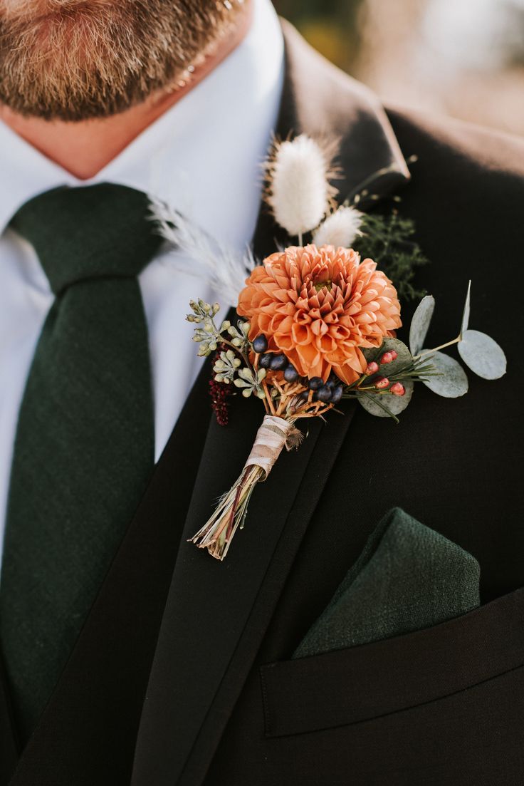 a man wearing a suit and tie with an orange boutonniere on his lapel