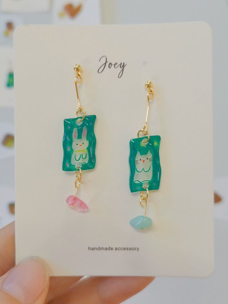 a pair of earrings with an image of a cat on the front and green background