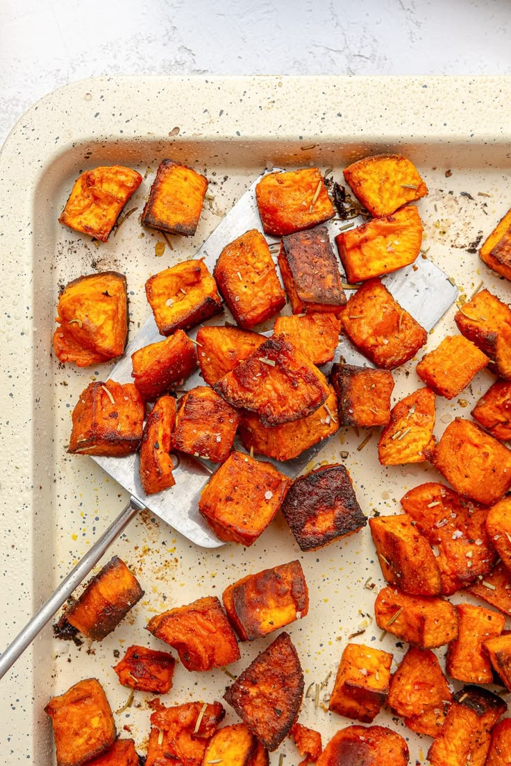 roasted sweet potatoes on a baking sheet with a spatula