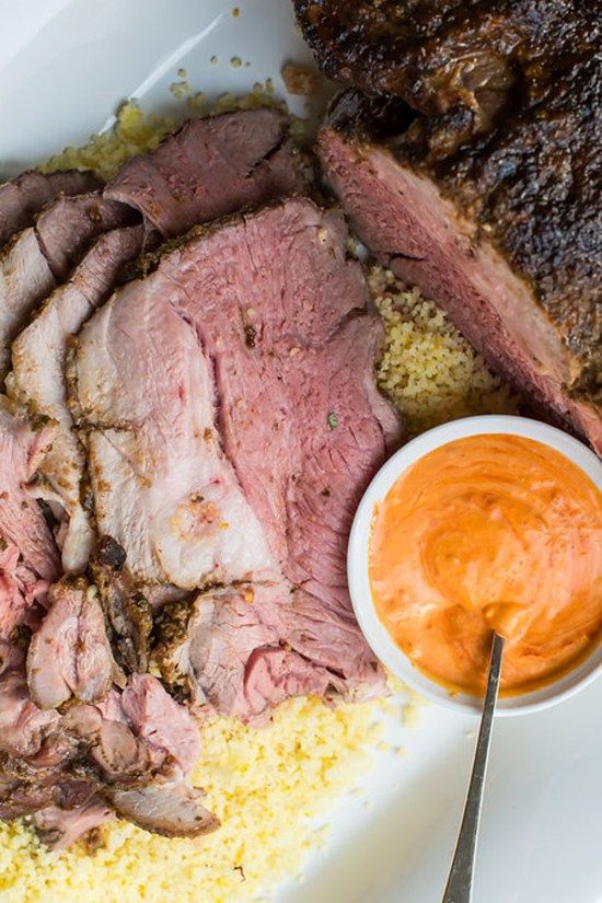 a white plate topped with meat and sauces next to a bowl of dipping sauce