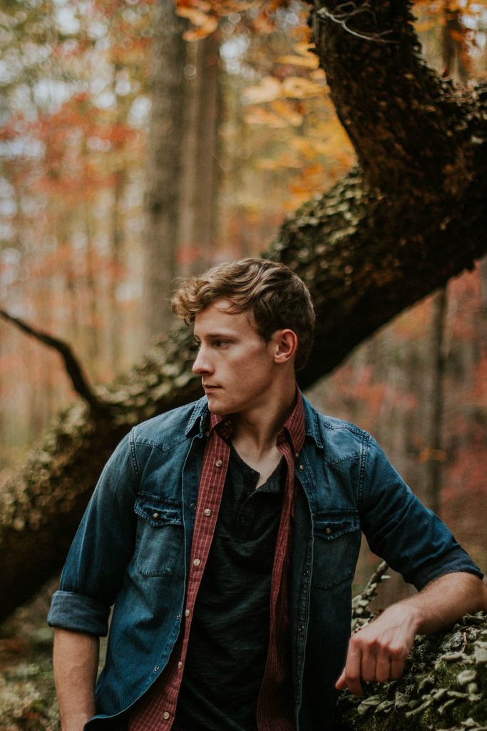 a man standing in the woods with his hands on his hips and looking off into the distance